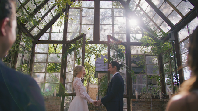 A man and woman getting married in an intimate setting inside a greenhouse