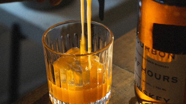 A cut crystal glass with an old fashioned being poured