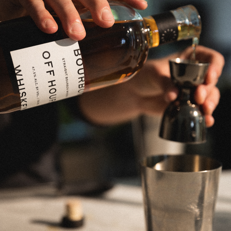 Hands mixing a cocktail with Off Hours Whiskey
