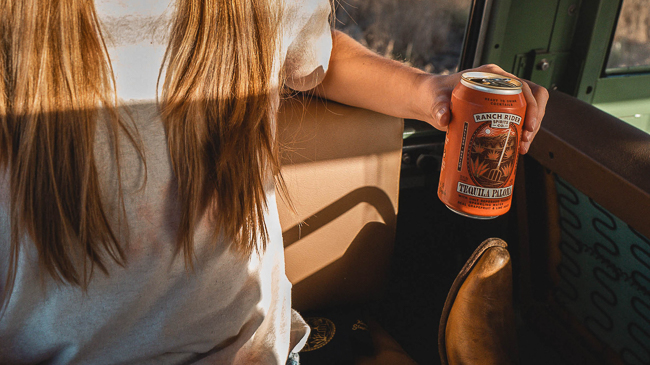 A girl holding a Ranch Rider in the back of a vintage Land Rover