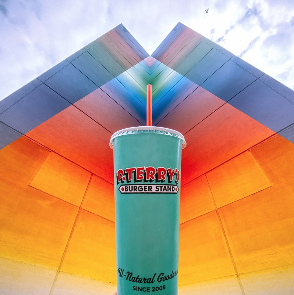 A P. Terry's cup in front of a local Austin mural