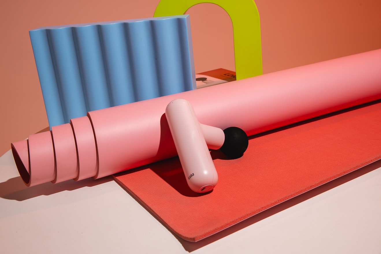 A still-life of the Lola massager with other fitness products