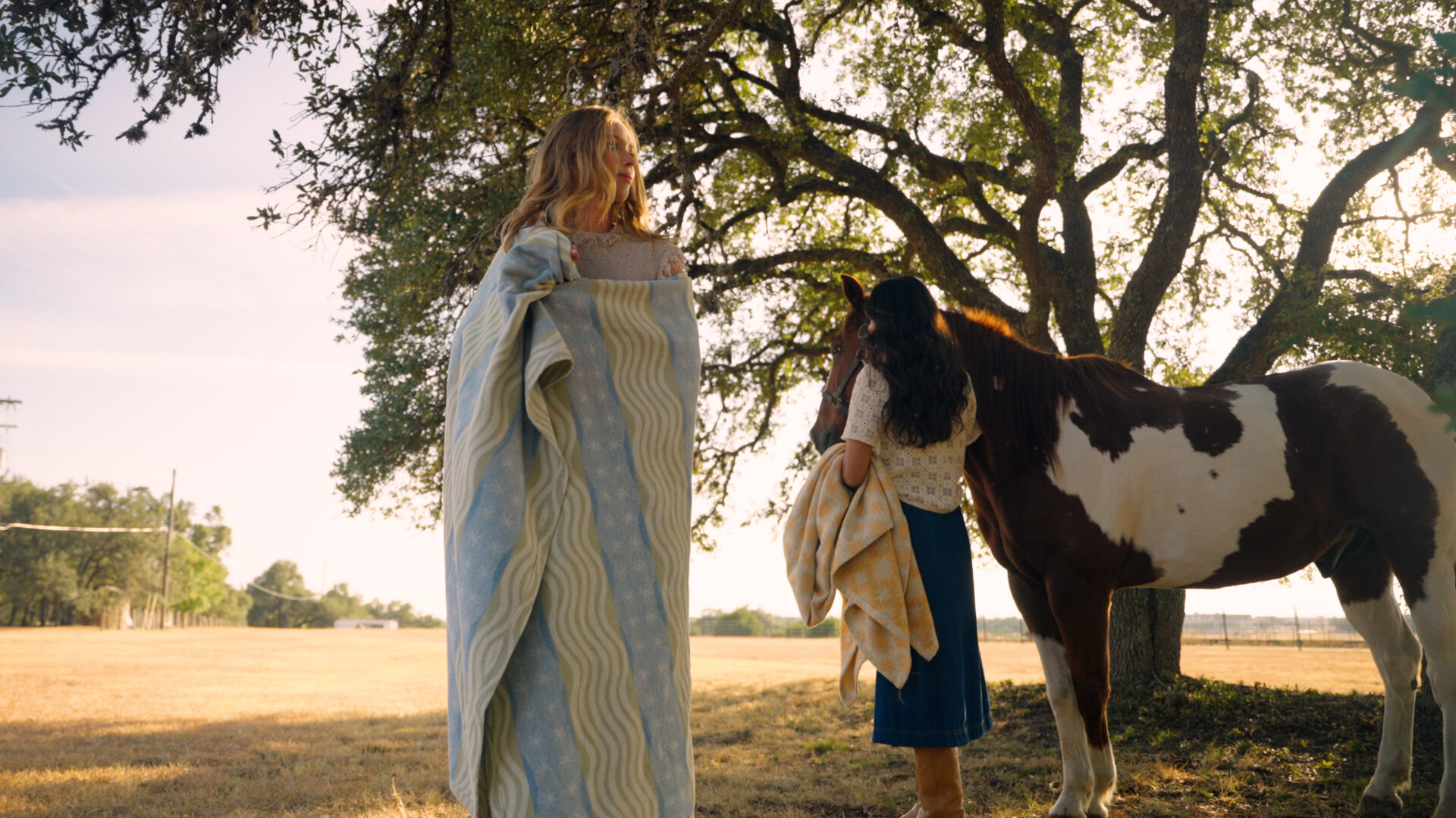 A woman wrapped in a Chappywrap blanket stands with a horse