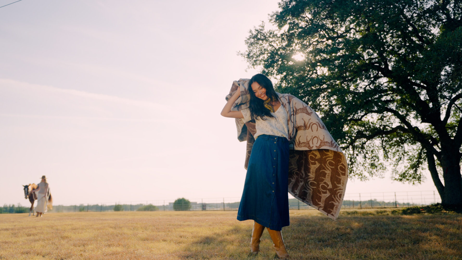 A woman in a large field on a ranch wrapped in a Chappywrap blanket