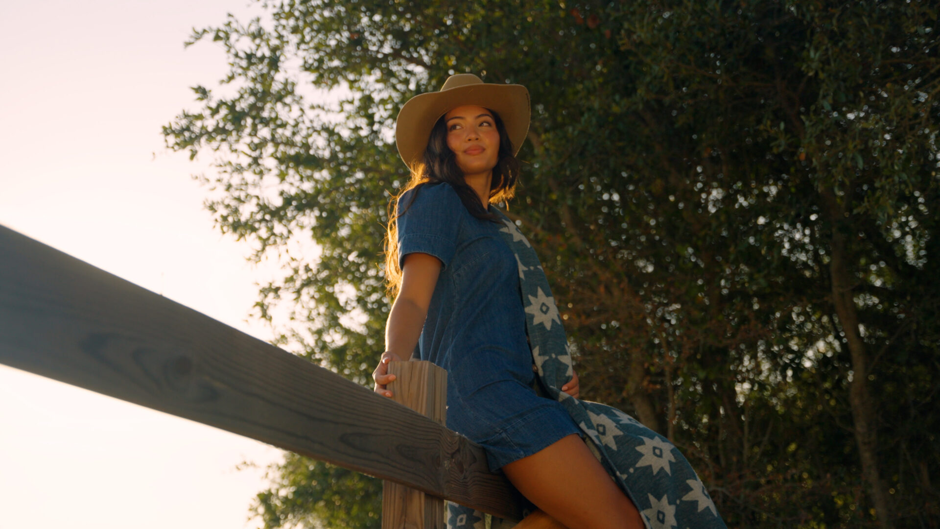 A woman sitting on a fence at a ranch
