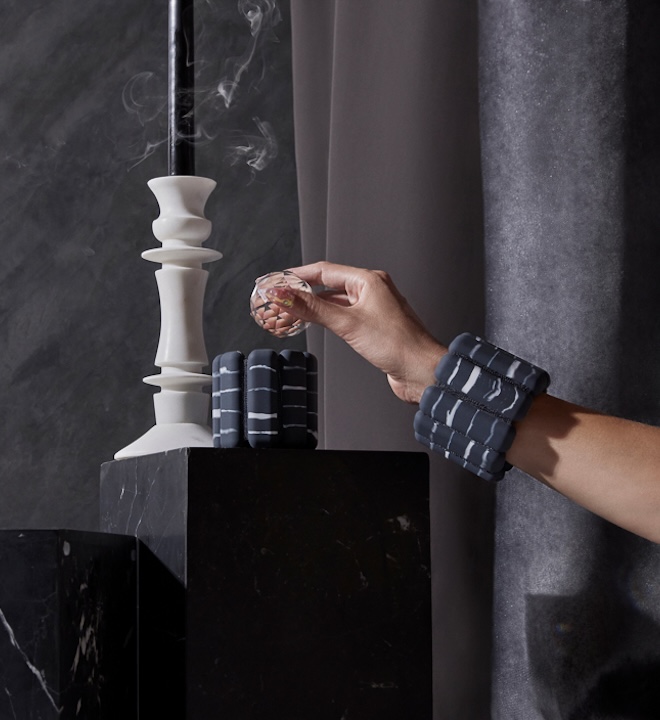 A hand wearing stone-colored Bala Bangles reaches toward a high-fashion inspired set